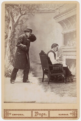 A black-and-white studio photograph of a White man wearing a hat and overcoat standing in a snow scene, and the same man seated inside by a fire reading a book.