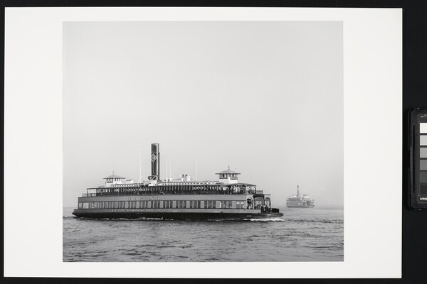 A black-and-white photograph of a large ferryboat on the water under a clear sky.