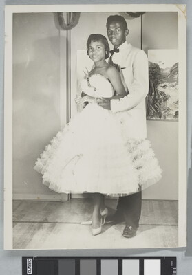 A black-and-white photograph of a Black couple in formal dress at a dance.