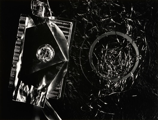 An abstract black-and-white photograph of what looks like pieces of metal or glass that create textures and circular patterns.