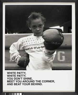 A black-and-white photograph of a Black girl wearing boxing gloves and looking at the camera above text that reads, "White Patty, White Patty, You don't shine. Meet you around the corner and beat your behind."