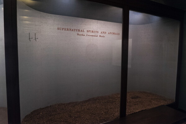 A color photograph of an empty museum display behind glass; the text on the wall reads, "Supernatural Spirits and Animals."