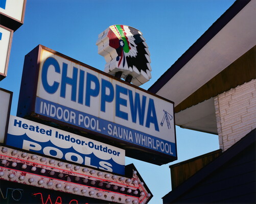 A color photograph of a large sign that reads, "Chippewa," advertising an indoor pool and sauna; a profile of a Native American head on its top.