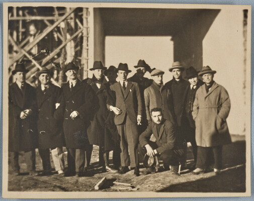 A black-and-white photograph of a group of White men, most wearing hats and overcoats, outdoors.
