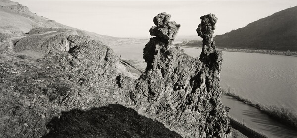 A black-and-white photograph of rock formation near a body of water.