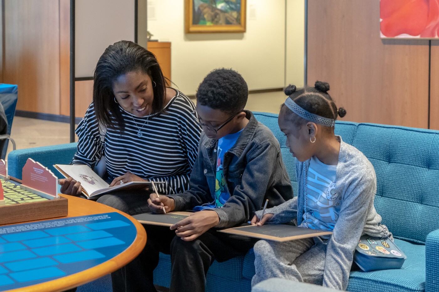 A family sits on a sofa at the Carter working on an art activity.