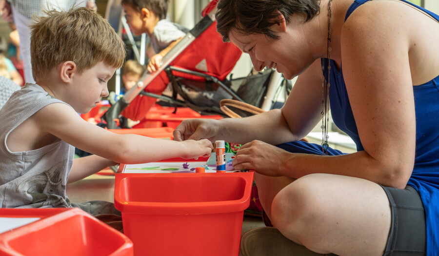 An adult and a child make art together at lap desks.