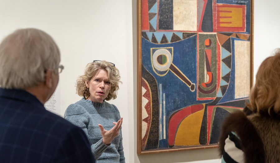 A Carter curator talks to guests in front of a painting.