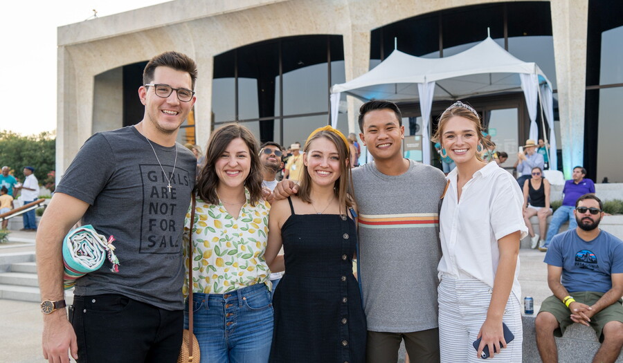 A group of young adults with their arms around each other stand in front of the Carter.