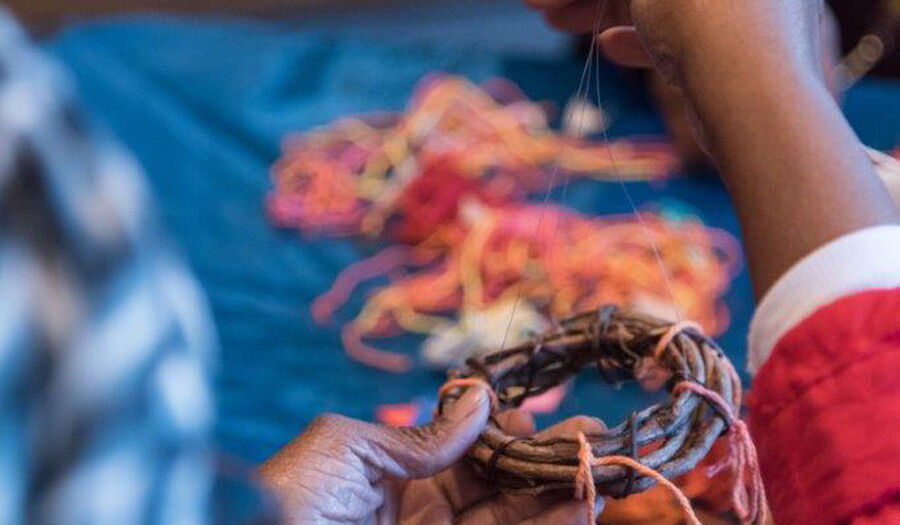 Close-up of a senior&#039;s hands using yarn and sticks to make an artwork.