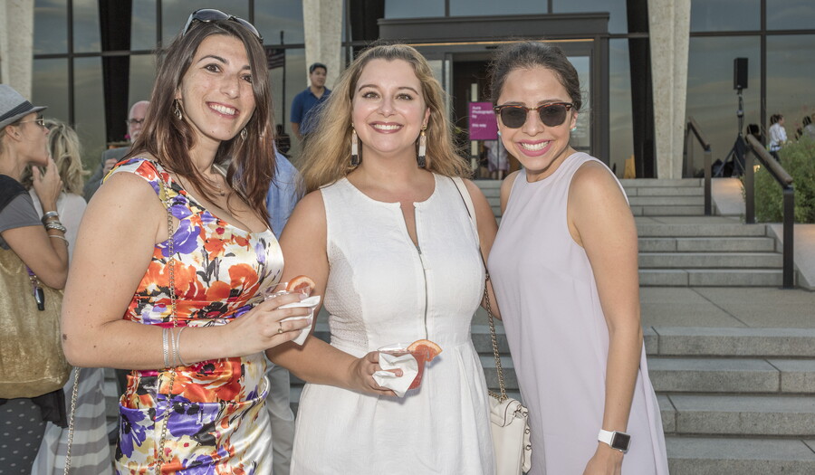 Three adults stand together in front of the Carter at a summer event. 