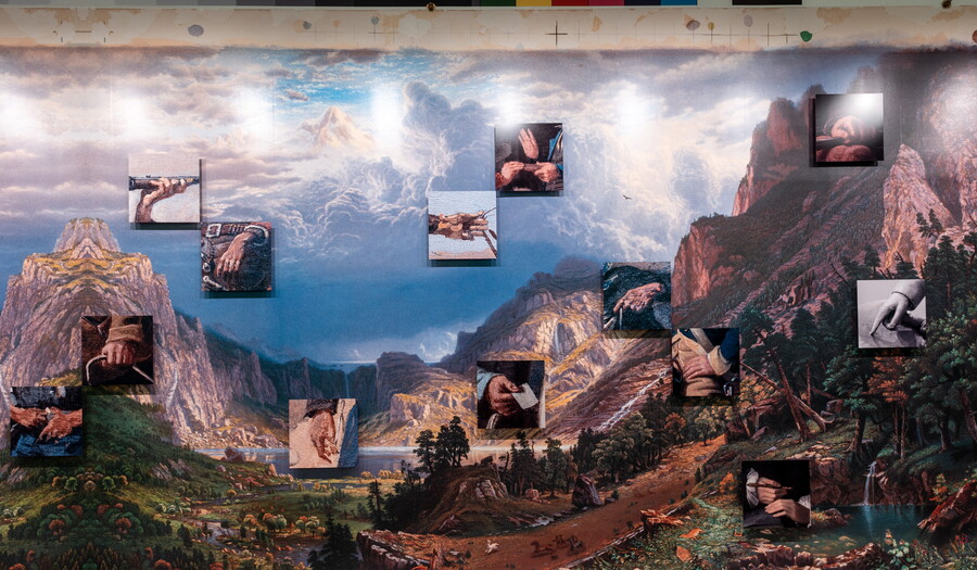 A view of a gallery wall with large-scale reproduction of an Albert Bierstadt print with close-up details from paintings and sculptures placed on top of it. 