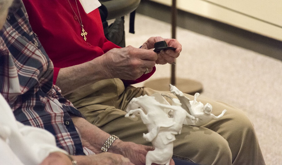 Elderly people hold printed replicas of sculptures in the Carter collection.