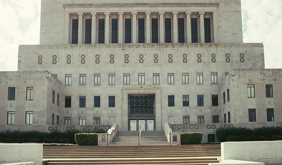 A multi-story stone building sits at the top of wide flights of steps.