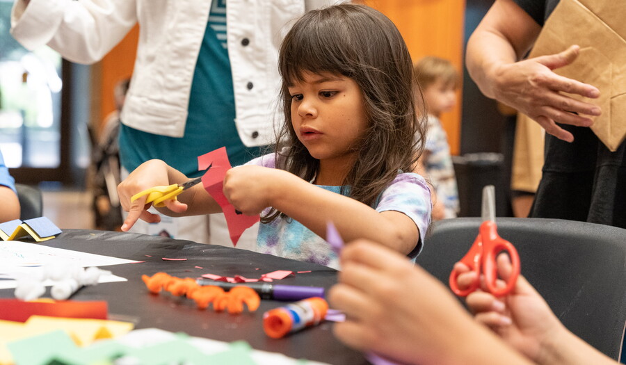 A small child makes artwork from colored construction paper.