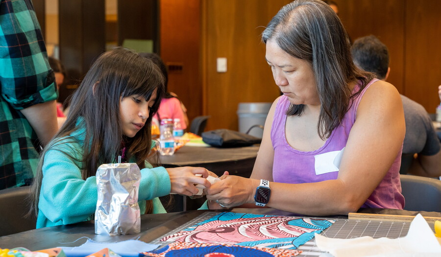 An adult and a child work on an art project together at a table in the Carter&#039;s Pop-up space.