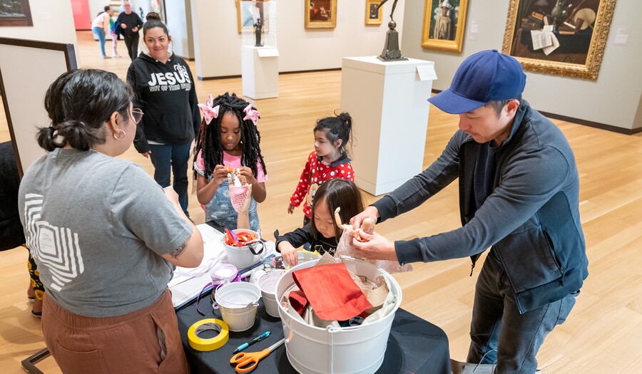 A group of adults and children in a Carter gallery at a table making artwork.