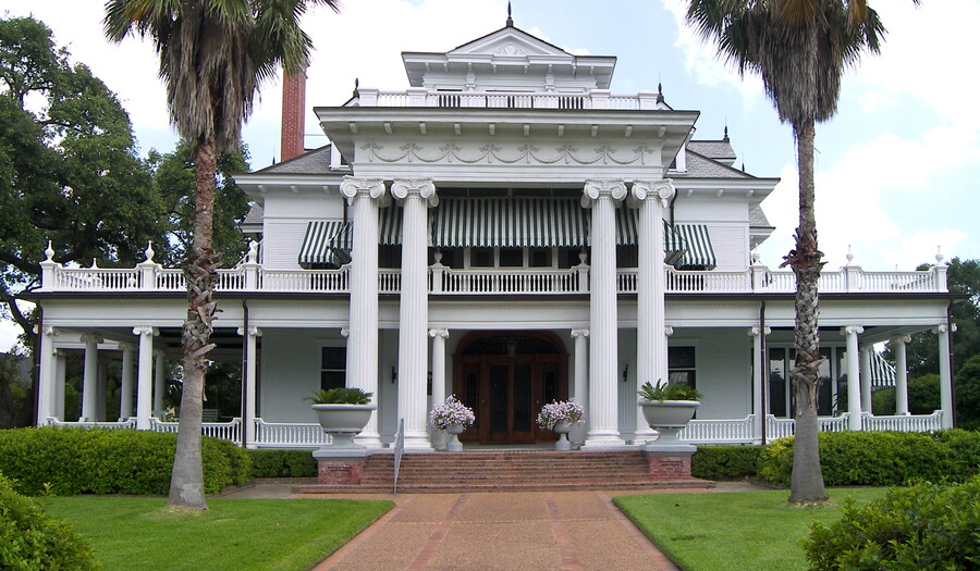 A large white mansion in the Beaux-Arts style with four large fluted columns flanking the entrance.