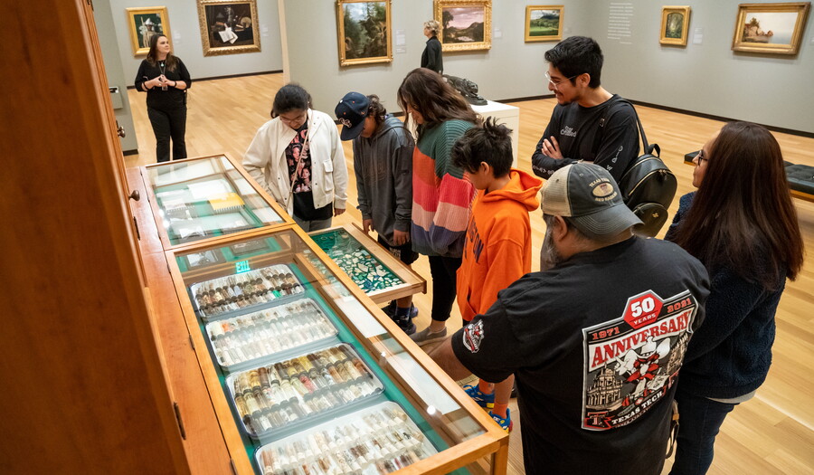 A group of people of a variety of ages stand in a Carter gallery looking at interactive artwork.
