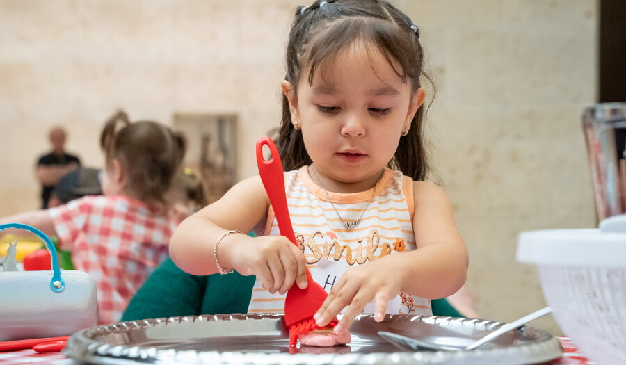 A child paints an object on a table in the Carter&#039;s Atrium.