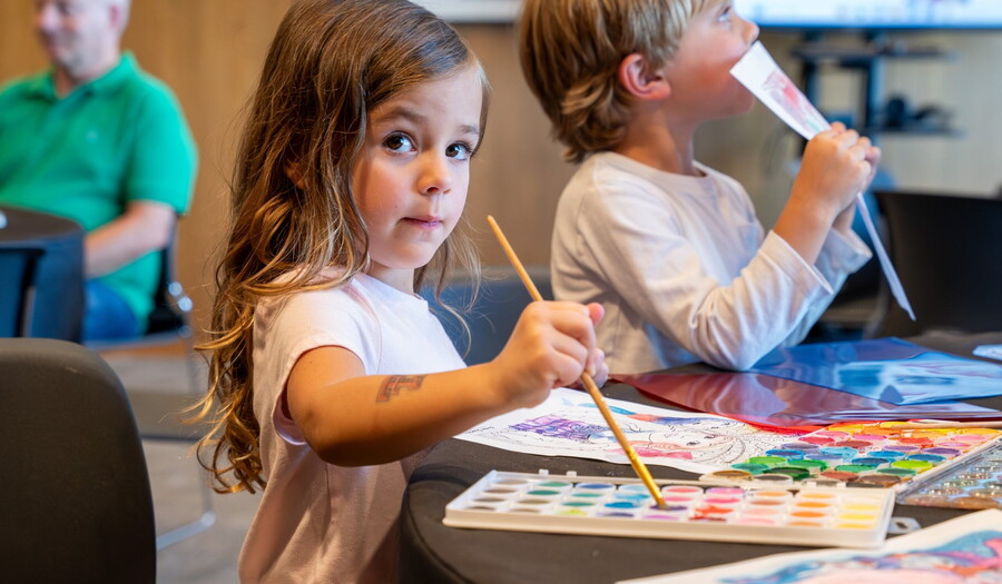 A young girl paints with watercolors at a table in the Carter&#039;s Pop-Up space.