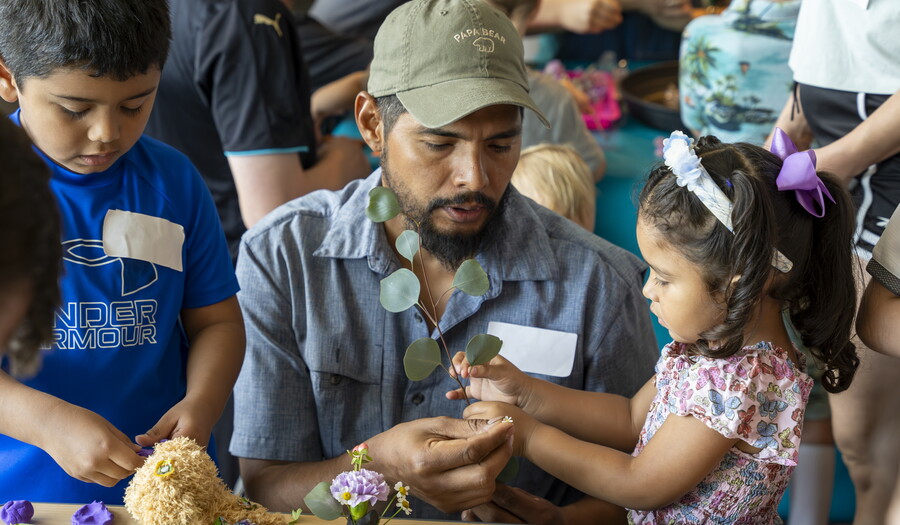 Two brown-skinned children and an adult make sculpture at table in the Carter&#039;s Pop-up Lounge.