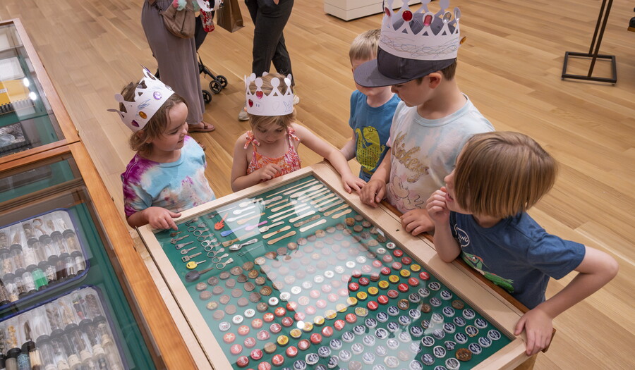 Five children stand around an open drawer in &quot;The Texas Cabinet&quot; looking at its contents.