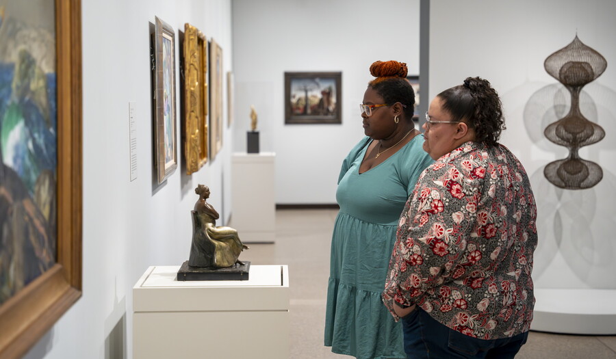 Two women look at artwork on the wall of a Carter gallery.