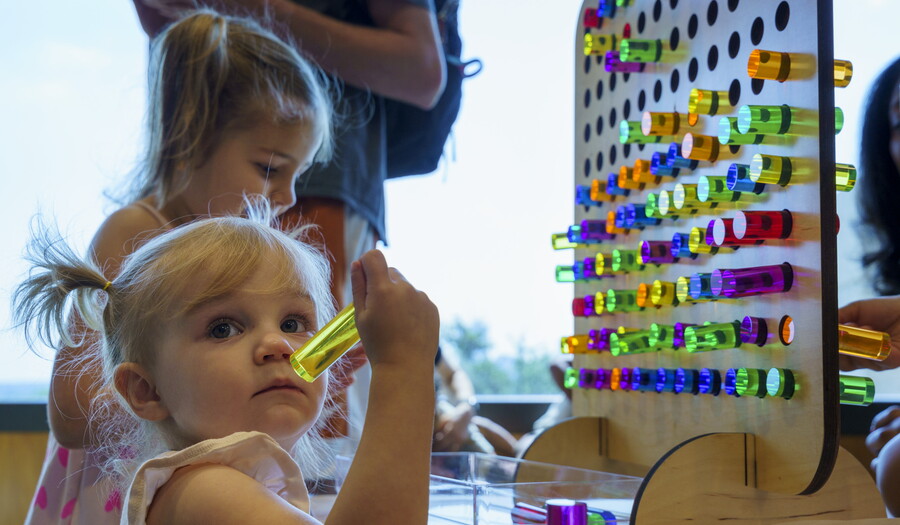 Two children play with large colored pegs and a pegboard in the Carter's Pop-Up Space.