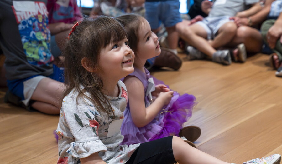 A close-up of two smiling White children sitting on the floor of a Carter gallery.