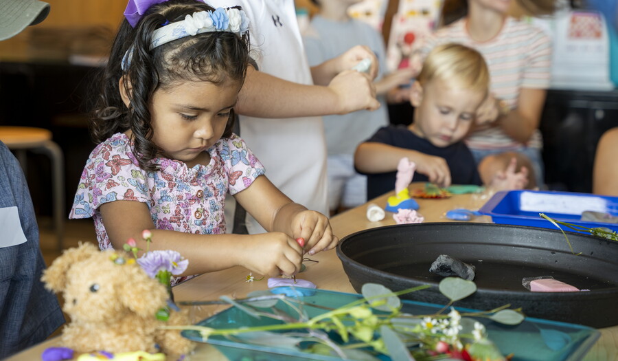 Two toddler-age children make art next to each other at a table in the Carter's Family Pop-Up Space.