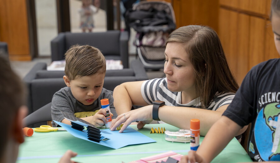 A young White woman and a child make art at a table in the Carter's Library.