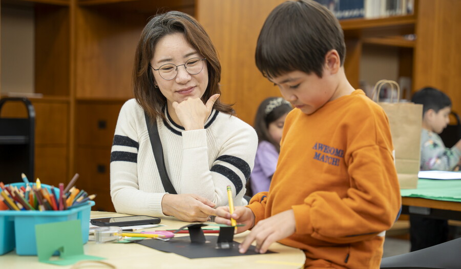 A woman and a child, both with Asian features, make artwork at a table in the Carter Library.
