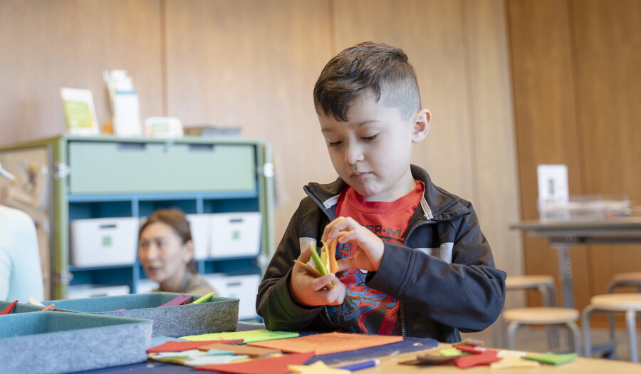A light-skinned child makes art at a table in the Carter's Family Pop-Up Space.