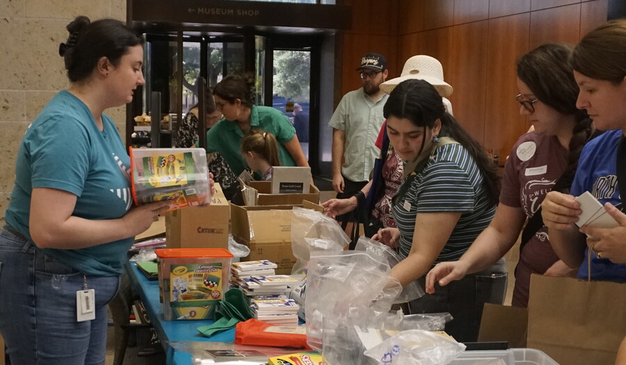 A group of adults look through art supplies at a table in the Carter's Atrium.