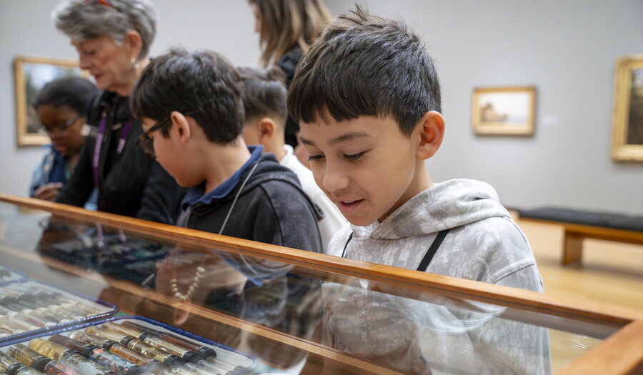 Medium-skinned children look at the objects in "The Texas Cabinet" in a Carter gallery.