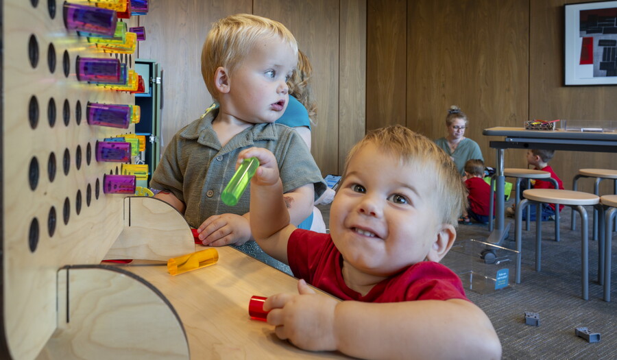 Two very young White babies play with colored pegs in the Carter's Family Pop-up Space.