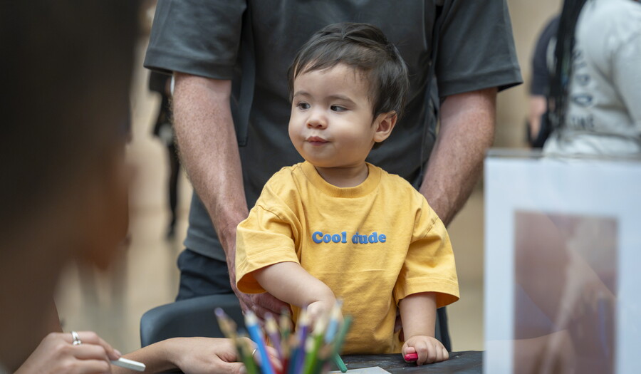 A small child uses crayons to color at a table in a Carter gallery.
