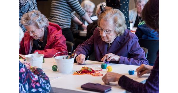 Seniors sit at a table and make art.