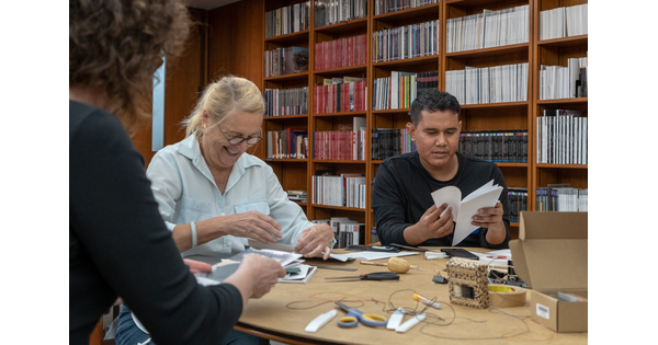 Two adults at a table make books.