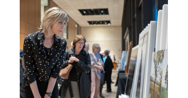 Adults lined up to look at artwork displayed on easels.