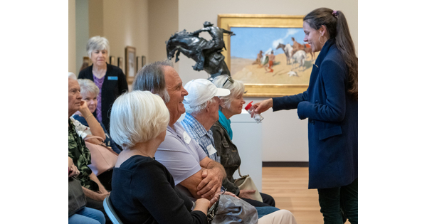 A group of senior adults smells a vial held by an educator in the Carter galleries.