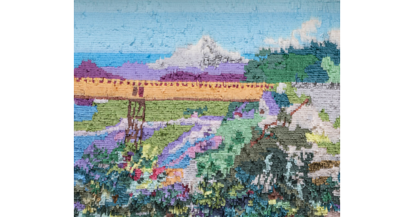 Mountain and bridge made out of colored tissue paper arranged like paint on a wall 