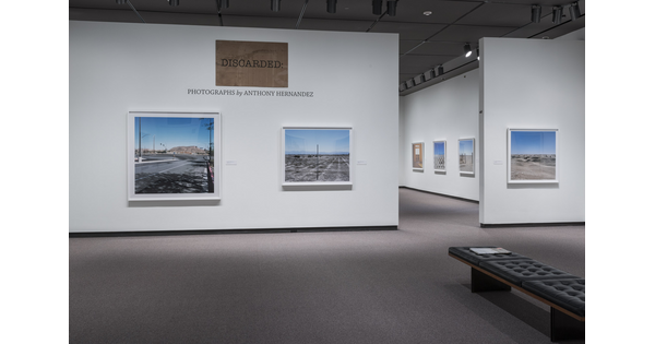 Overview of gallery entrance showing the exhibition title and two artworks to the left of a doorway into the exhibition.