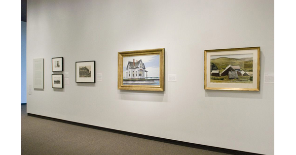 On a cream-colored gallery wall hangs three framed prints and two framed paintings.