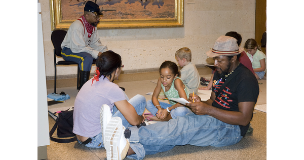 Families sit on the floor of a Carter gallery working on art projects.