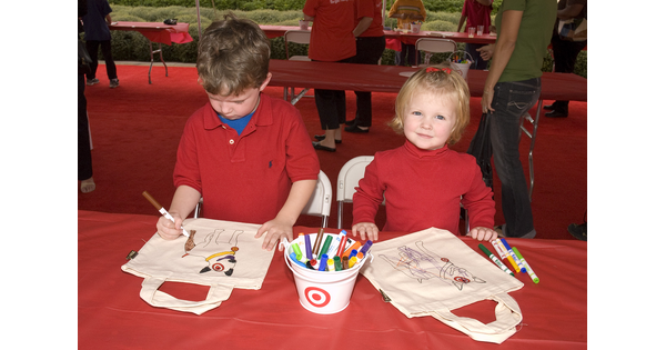 Two children coloring on canvas bags.