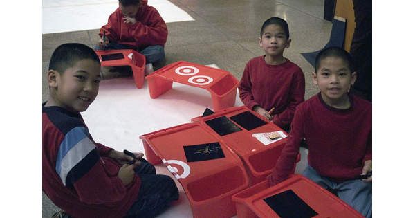 Three children sit on the floor working on art activities at the Carter.