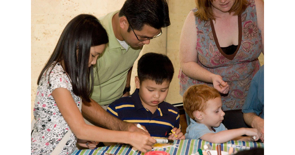 A family gathers around a table to work on an art activity.