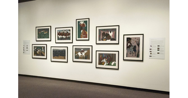 A cream-colored gallery wall with nine framed prints hanging on it.